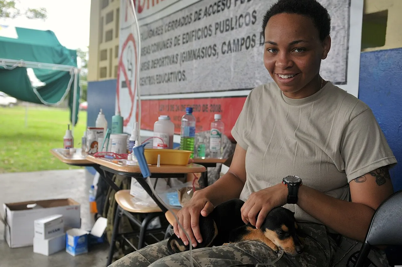 Técnica veterinaria sonríe mientras sostiene a un cachorro durante una jornada de vacunación
